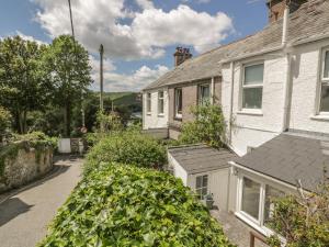 a white house with a gray roof and some bushes at Lowena Cottage in Looe