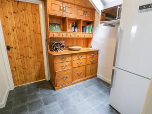 a kitchen with wooden cabinets and a refrigerator at Llety Perygl in Harlech