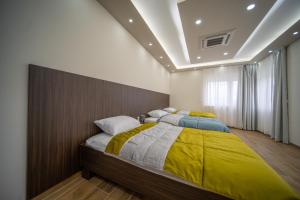 a bedroom with two beds with yellow and gray blankets at Al Hayat Apartments in Vogošća