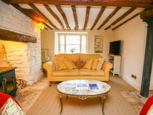 a living room with a couch and a table at Murton Cottage in Burford