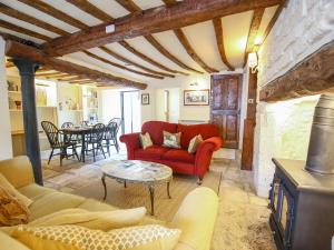 a living room with a red couch and a table at Murton Cottage in Burford