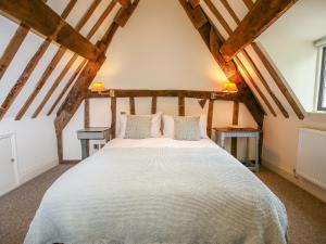 a bedroom with a large white bed with two tables at Murton Cottage in Burford