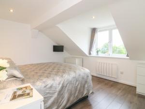 a white bedroom with a bed and a window at Cuckoo Cottage in Bridport