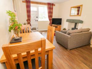 ein Wohnzimmer mit Tisch und Couch in der Unterkunft Tilberthwaite Farm Cottage in Coniston