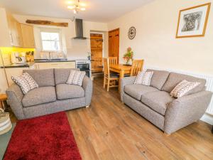 a living room with two couches and a kitchen at Tilberthwaite Farm Cottage in Coniston