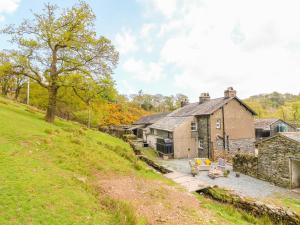 an old stone house on a grassy hill at Tilberthwaite Farm Cottage in Coniston