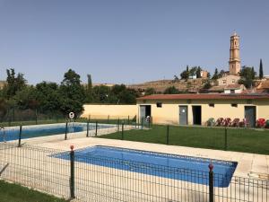 a swimming pool with a fence in front of a building at Casa María in Samper del Salz