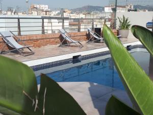 a swimming pool with two lounge chairs on a roof at Silken Ramblas in Barcelona