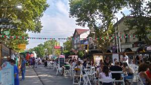 Une foule de gens assis à des tables dans une rue de la ville dans l'établissement Aloha III - El Palomar B&D, à El Palomar