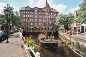 ein Boot in einem Kanal vor einem Gebäude in der Unterkunft Hotel Zur Mühle in Buxtehude