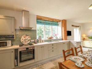 a kitchen with white cabinets and a table with a dining room at The Old Laundry in North Tawton