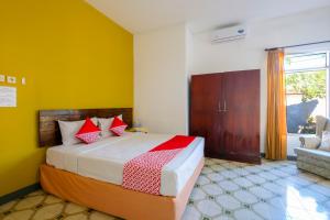 a bedroom with a bed with yellow walls and a window at OYO 1206 Lombok Guest House in Mataram