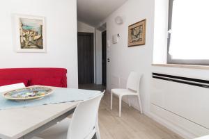 a white dining room with a table and white chairs at Borgo Fratta Holiday Houses in Umbertide