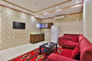 ein Wohnzimmer mit einem roten Sofa und einem TV in der Unterkunft OYO 273 Star Yanbu Hotel Suites in Yanbu