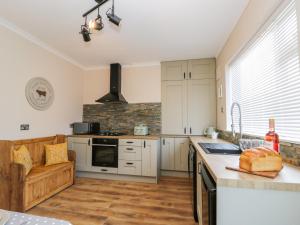 uma cozinha com armários brancos e uma bancada em Benjamin Cottage em Redcar