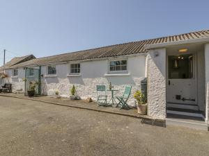 une maison avec deux chaises et une table devant elle dans l'établissement Falconers Cottage, à Holyhead