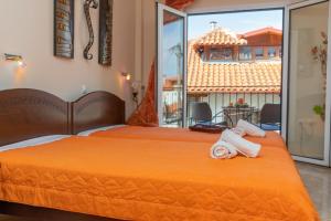 a bedroom with two beds with orange sheets and a balcony at Guesthouse Nefeli in Litochoro