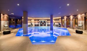 een groot zwembad met blauw water in een gebouw bij Hotel Le Hameau Du Kashmir in Val Thorens