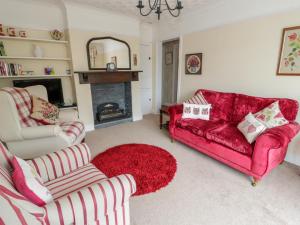 a living room with a red couch and a fireplace at Stonyway in Benllech