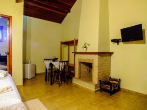 a living room with a fireplace with a table and a tv at Pousada Vista da Serra Monte Verde in Monte Verde