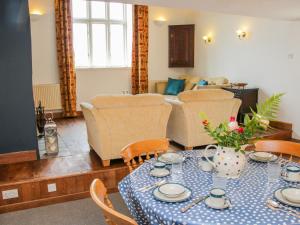 een woonkamer met een tafel en stoelen en een bank bij Graig Gwyn Cottage in Oswestry