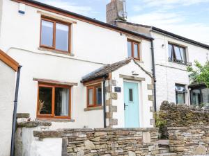 a cottage with a blue door and a stone wall at Windmill Cottage in Blackburn