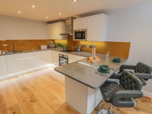 una cocina con armarios blancos y una gran isla con sillas en Premier, Transit & Lady Hilda Engine Shed, en Whitby