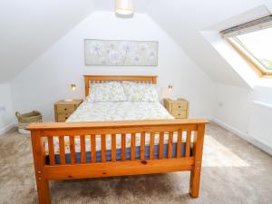 a bedroom with a wooden bed in a attic at 5 Yarmouth Cottages in Freshwater