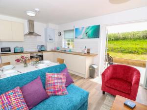 a living room with a blue couch and a kitchen at 5 Yarmouth Cottages in Freshwater