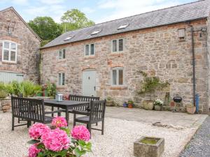 a stone house with a table and benches in front of it at Graig Gwyn Cottage in Oswestry