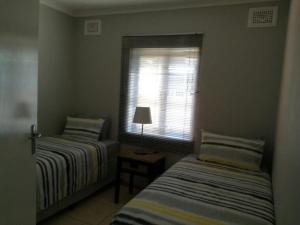 a bedroom with two beds and a window with a lamp at The Crescent Guesthouse on Waterfall in Durban