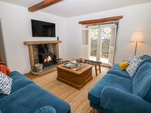 ein Wohnzimmer mit 2 blauen Sofas und einem Kamin in der Unterkunft River Cottage Hayfield in Highpeak Junction
