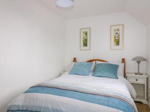 ein Schlafzimmer mit einem großen Bett mit blauen Kissen in der Unterkunft Sarah's Cottage in Padstow
