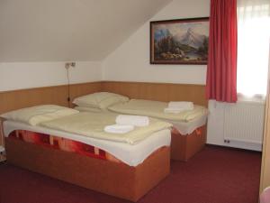two twin beds in a room with a red curtain at Šindlerův Dvůr in Krmelín