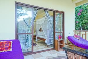a room with a balcony with purple furniture at Ifa Beach Resort in Jambiani