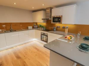 cocina con armarios blancos y suelo de madera en Premier, Transit & Lady Hilda Engine Shed, en Whitby