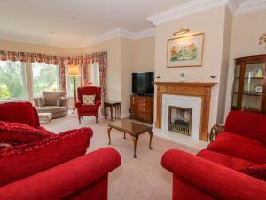 a living room with red furniture and a fireplace at Sevenacres in Kelso
