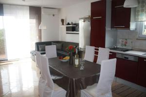 eine Küche mit einem Tisch mit weißen Stühlen und einem Esszimmer in der Unterkunft Apartman Antonia in Poreč