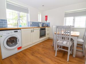 a kitchen with a washing machine and a table at Well House Farm Flat 1 in Chester