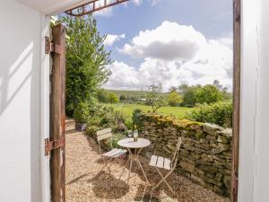 an open door to a patio with a table and a stone wall at The Studio in Shaftesbury