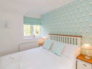 a bedroom with a white bed and a blue wall at Duck Cottage in Weymouth