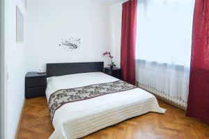 - une chambre avec un lit doté de draps blancs et de rideaux rouges dans l'établissement Modern Apartment Navrátilova II, à Prague