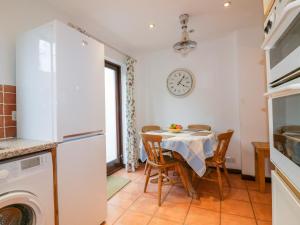 eine Küche mit einem Tisch mit Stühlen und einer Uhr an der Wand in der Unterkunft Sarah's Cottage in Padstow