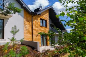 a wooden house with a black roof at Sun & Sport Apartamenty Krynica-Zdrój in Krynica Zdrój