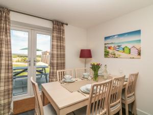 Un comedor con mesa y sillas y una ventana. en Ocean Breeze, en Marazion