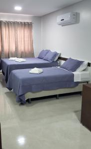 two beds in a room with blue sheets and pillows at Flats Grangeiro in Crato