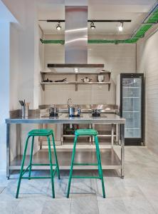 a kitchen with two green stools in front of a counter at Hola Hostal Collblanc in Hospitalet de Llobregat