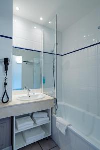 La salle de bains est pourvue d'un lavabo, d'une douche et d'une baignoire. dans l'établissement Résidence Biarritz Ocean, à Biarritz