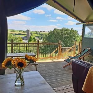 a vase of flowers on a table on a deck at Brackenhill Glamping - Safari Tent with Hot Tub in Ivybridge