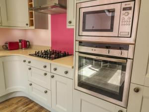 a kitchen with a microwave and a stove at 3 Top View Cottages in Salcombe